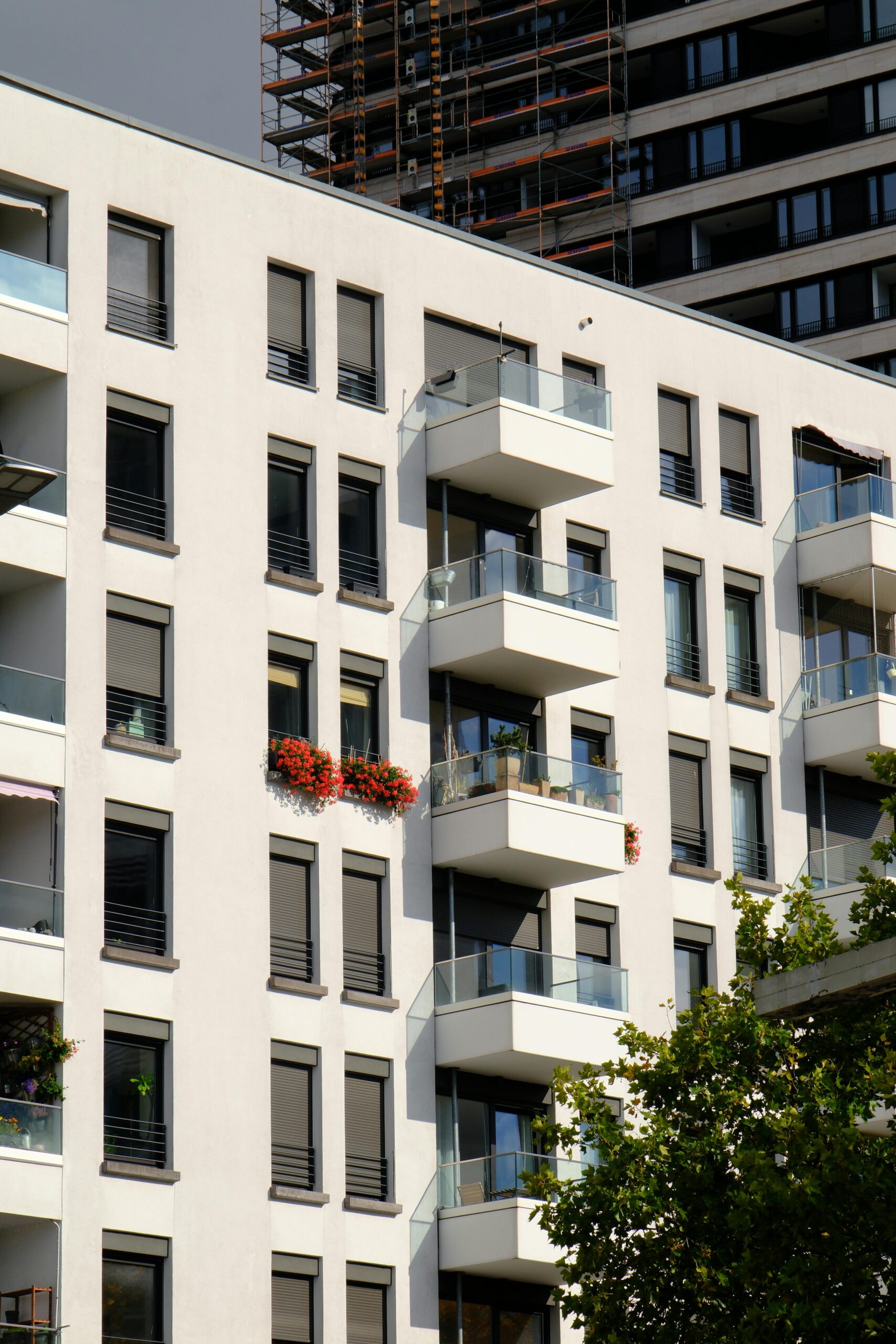 Contemporary apartment building with glass balconies and floral decor in urban setting.