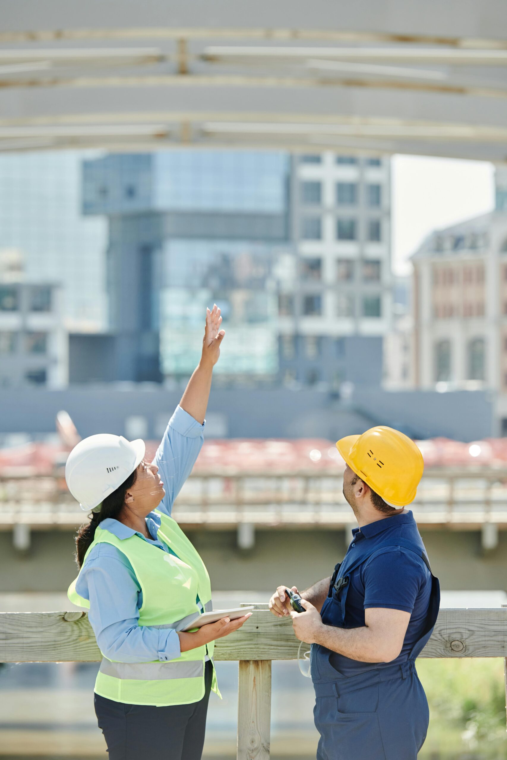 Two architects discussing plans at a city construction site with high-rise buildings.